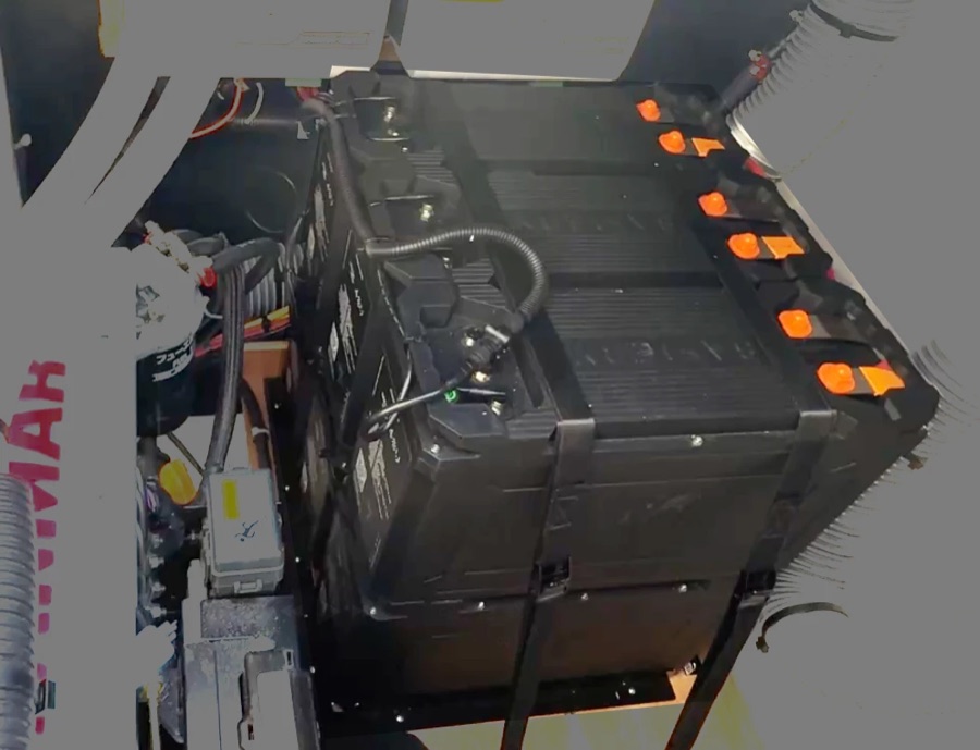 Safiery 48V 3C Solid State packs stacked and strapped beside an engine, with orange power terminals